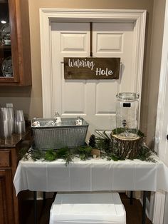 a white table topped with baskets filled with plants next to a wooden sign that says wedding hole