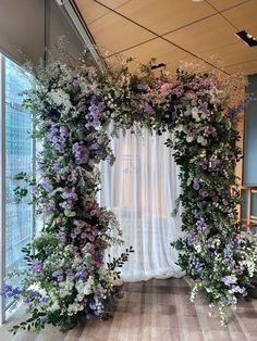 an arrangement of flowers and greenery on the side of a wall in front of a window