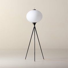 the floor lamp is white and has a black tripod base with a light bulb on top