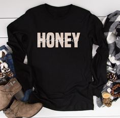 "Blessed Honey T-Shirt, Honey long sleeve shirt, Honey Life T-Shirt,Mother's Day Gift, Cute Honey Tee, Grandma Gift for the Holiday Christmas HOW TO ORDER 1. Select the shirt \"Style and Size\" 2.Select the shirt Color 3. Enter what would you like to say on your t shirt and LETTERING color 4.Select the quantity. 5. Click Add to cart.       If you have any difficulties, send us a message. Processing Time and Shipping The standard processing time is 1-3 business days. We usually proses and ship out the orders the next business day.   USA Orders: Standard : Takes 3 to 5 days to get delivered Priority : Takes 2 to 4 days to get delivered Express: Takes 1 to 2 days to get delivered   METERIALES High Quality Heat Transfer Vinyl, Unisex Shirt DESCRIPTION Please see the sizing chart for choosing y Long Sleeve T-shirt With Lettering, Winter Graphic Tee With Long Sleeves, Winter Graphic Long Sleeve T-shirt, Winter Long Sleeve Graphic Tee, Long Sleeve Text Print T-shirt For Winter, Winter Long Sleeve Tops With Lettering, Black Long Sleeve Top As Gift, Black Long Sleeve Top As A Gift, Long Sleeve Graphic Tee T-shirt As Gift