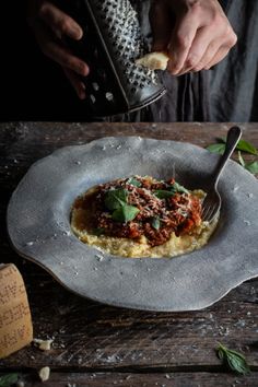 a person is holding a grater over some food on a plate with parmesan cheese