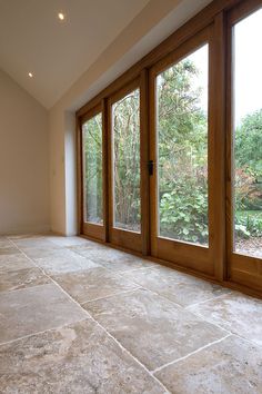 an empty room with large windows and stone flooring