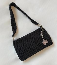 a black crocheted purse with a butterfly charm hanging from it's side