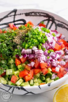 a bowl filled with chopped vegetables and garnished with seasoning next to an orange slice