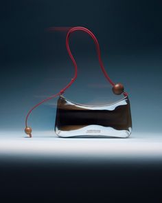 a black and silver purse with red string attached to it's handle, on a blue background