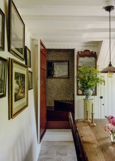 a dining room table with flowers and pictures on the wall