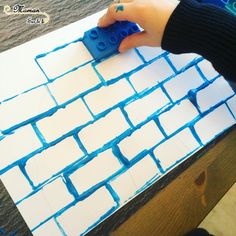 a person is making a brick wall out of lego blocks with blue paint on it