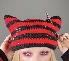 a woman wearing a red and black knitted cat hat with scissors on her head