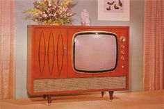 an old fashioned television sitting on top of a wooden cabinet in front of a vase with flowers