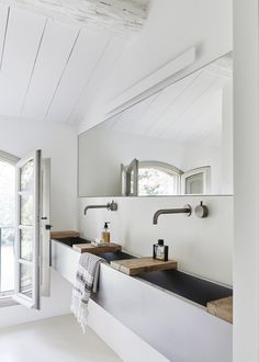 a white bathroom with two sinks and mirrors