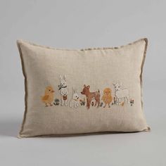 an embroidered pillow with farm animals on the front and back, sitting on a grey surface