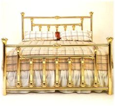 a gold metal bed with plaid sheets and pillows