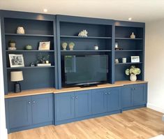 a living room with blue bookcases and a flat screen tv on the wall