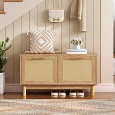 a wooden cabinet sitting in front of a stair case next to a potted plant