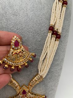 Small Pearl Rani Haar with CZ Red Stone Pendent with matching earringsColor : Pearl WhiteSize : Mala Length : Approx 22 Inches; Earrings Length : 1.5 InchesStones : Red Stone AD Pearls Rani Haar, Pearl Mala, Red Stone, Indian Jewelry, Pearl White, Statement Necklace, Stone, Red