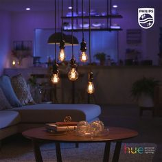 a living room filled with furniture and hanging light bulb chandelier over the coffee table