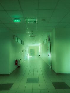 an empty hallway with green light coming from the ceiling