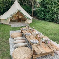 a table set up with plates and place settings in front of a teepee tent