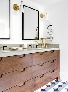 a bathroom with two sinks and mirrors on the wall next to a rug in front of it