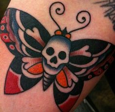 a skull and butterfly tattoo on the back of a woman's arm, with an orange ribbon around it