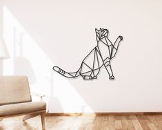 a paper cut cat sitting on top of a wooden floor next to a white wall