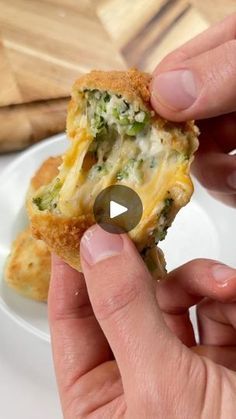 a person holding a piece of food with broccoli and cheese in it on a white plate