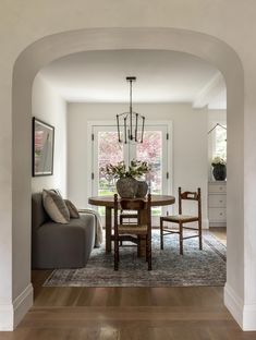 a living room with a couch, table and chairs next to a doorway that leads into the dining area