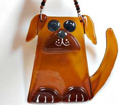 a brown dog shaped purse hanging from a hook on a white wall with beads around it's eyes