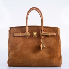 This rare vintage Birkin is a luxurious masterpiece that speaks volumes of refined elegance and unique texture. Crafted from sumptuous Doblis suede, this bag exudes a soft, velvety touch that is both visually appealing and delightful to hold. The Fauve color, a rich and warm hazelnut brown, adds a depth of sophistication and earthy charm to the bag’s appearance. Complementing the suede’s luxurious texture is the Nubuck trim, which provides a subtle contrast with its slightly smoother finish, this material is also used to line the bag. The gold hardware on this Birkin adds a classic touch of glamour, creating a beautiful harmony with the bag's earthy tones. Given its vintage from 1997, this Birkin is not just a fashion statement but a piece of Hermes history, showcasing the brand’s timeless Rare Hermes Bags, Hermes History, Brown Birkin, Vintage Birkin, Vintage Hermes Bag, Vintage Kelly, Timeless Bags, Hermes Birkin 35, Hermes Kelly Bag