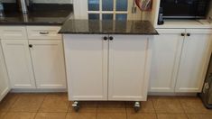 a kitchen with white cabinets and black counter tops on casteors to the door way