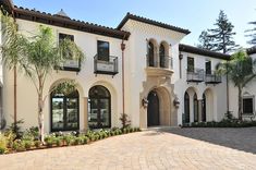 a large white house with lots of windows and palm trees in front of the building