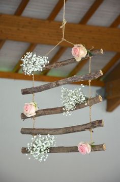 a mobile made out of branches with flowers hanging from it's sides and some baby's breath