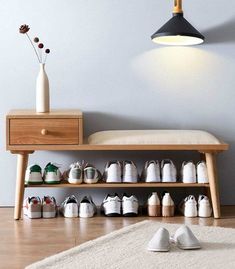 a wooden shoe rack with many pairs of shoes on it next to a white rug