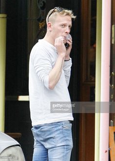 a man talking on his cell phone while standing in front of a building with the door open