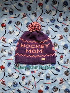 a purple knitted hat with the words hockey mom written on it