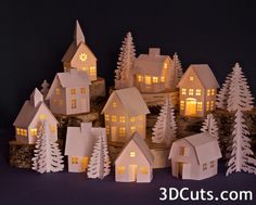 paper houses are lit up in the night with trees and snow around them on a table