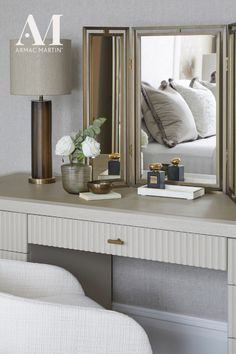 a mirror sitting on top of a desk next to a lamp and a vase with flowers