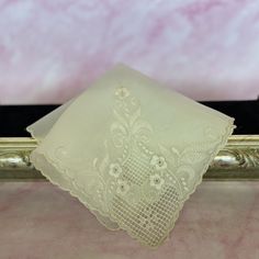 This fine off white sheer hanky has a gorgeous floral embroidery. The embroidered flowers are on one corner and include intricate cutwork with a bit of gray hue to it. The color is a deep off white - ecru color. According to the information given at the estate sale in which it was purchase, this hanky is made from sheer bamboo fibers and in the Philippine's. It also does resemble the type of lace embroidered pina cloth made in the Philippines - and could be made from pineapple fibers. A perfect bridal keepsake handkerchief. It measures 11" X 11". It is in good vintage condition with no issues noted.  Great quality for a bridal gift. Please see all photos for more details. This  vintage handkerchief can fill the need of "something old". Elegant Cream Embroidered Fabric And Notions, Elegant Machine Embroidered Handkerchiefs For Gifts, Elegant Lace Work Handkerchiefs Gift, Cream Handkerchiefs With Lace Trim For Weddings, White Floral Embroidery Handkerchiefs For Gift, Elegant White Handkerchiefs With Lace Work, White Flower-shaped Handkerchiefs As Gift, Embroidered Cream Handkerchiefs For Wedding, Elegant White Handkerchiefs With Machine Embroidery