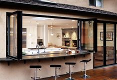 an outdoor bar with four stools in front of it and a kitchen behind it