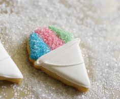 two decorated cookies on a table with white frosting and colored sprinkles