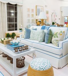 a living room filled with white furniture and lots of pillows on top of it's couches