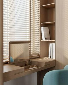 a desk and chair in a room with wooden blinds on the window sill, along with bookshelves