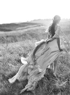 a woman in a white dress is walking through the grass