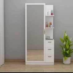 a white cabinet sitting next to a potted plant