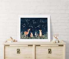 an art print of foxes and stars in the night sky on a wooden dresser next to a white brick wall