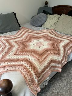 a crocheted blanket sitting on top of a bed next to pillows and blankets