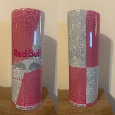 two red bull energy drink cans sitting on top of a wooden table next to each other