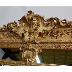 an ornate gold framed mirror is shown against a white wall