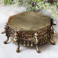 an ornately decorated wooden table with candles on the top and bottom, sitting in front of a tree