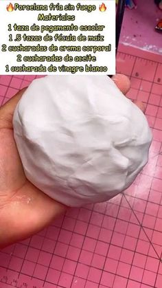 a person holding a fake white ball on top of a pink table next to a piece of paper